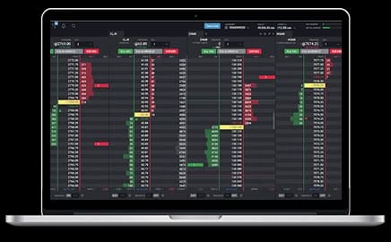 MacBook Pro displaying a futures trading platform interface with live market charts and trading tools on the screen.